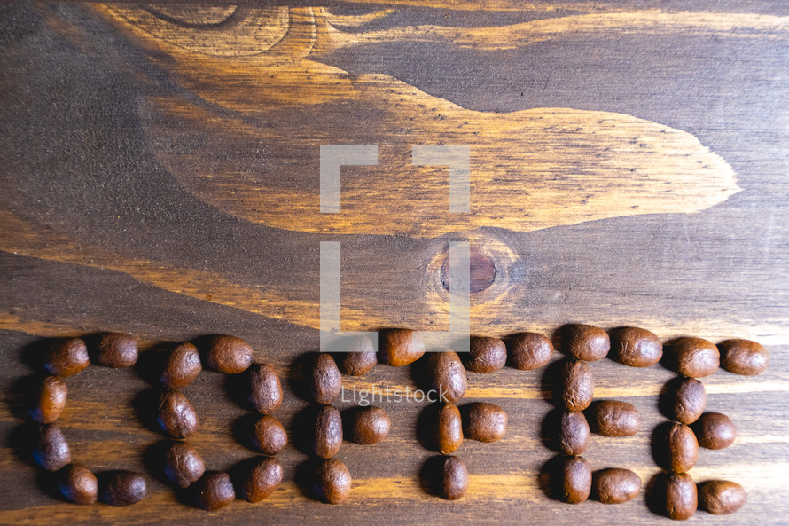 Coffee beans shaped in the letters coffee on a wooden background. Decorative banner for coffee products.