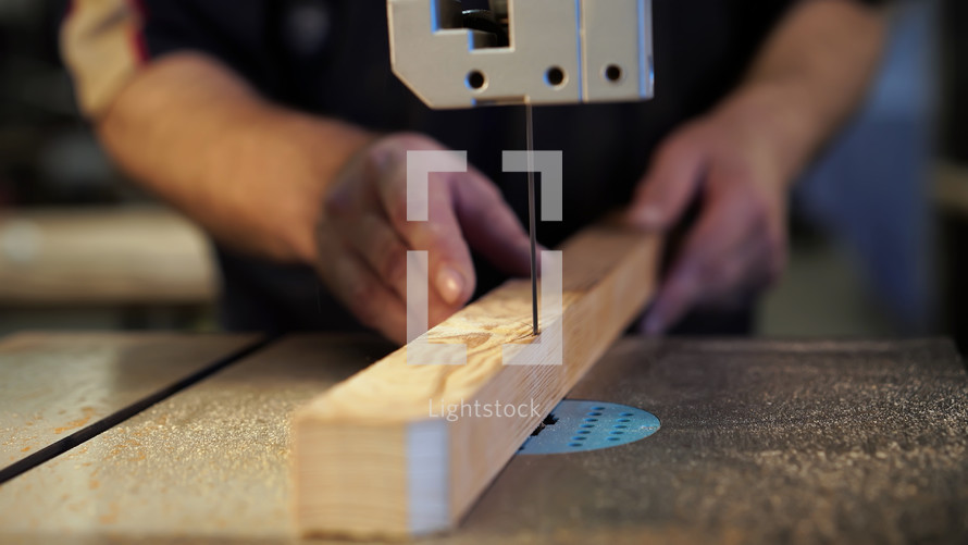 Handwork, carpentry concept, woodworking. Carpenter working in in factory atelier. Joiner labourer cuts wooden plank on jigsaw machine. High quality photo