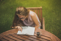 a young woman reading a Bible in her backyard 