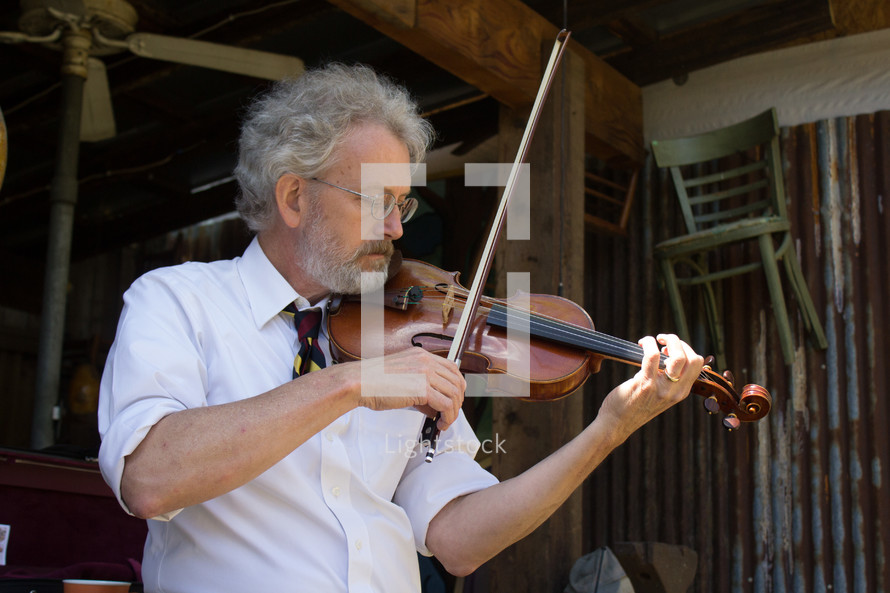 a man standing in a barn playing a fiddle 