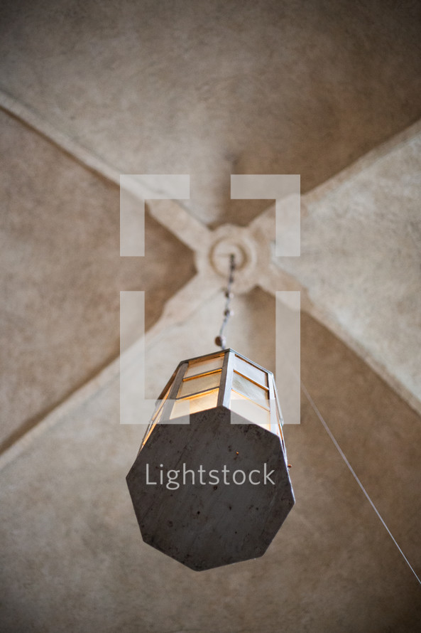 A lantern hanging from a church ceiling 