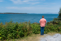 man standing on a shore looking out at the water 