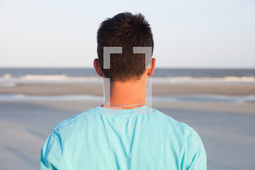back of a man's head on a beach 