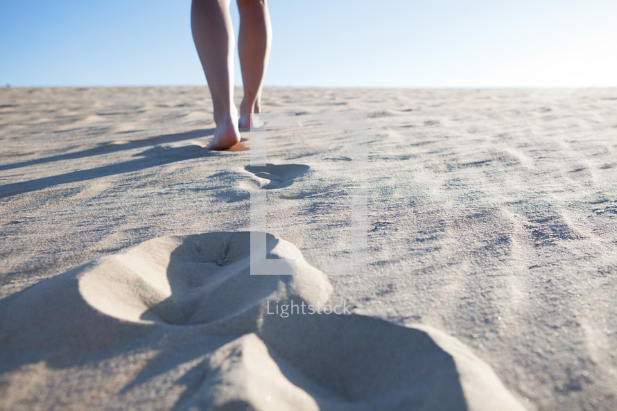 woman walking in the sand leaving tracks 