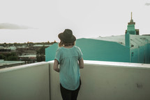 a woman standing on a rooftop looking over a railing 