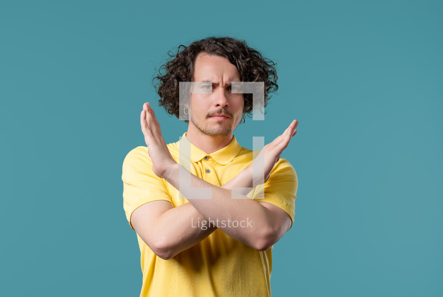 Serious dissatisfied man disapproving with no sign, refuse offer, nods head disapprovingly. Denying, Rejecting, Disagree, Portrait of young guy on blue, negative answer. High quality