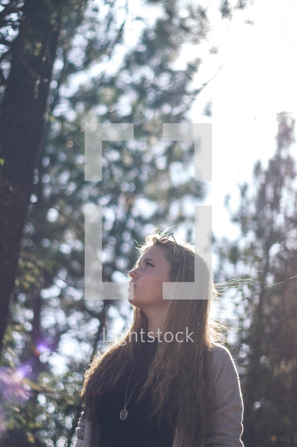 teen girl in a forest looking up 