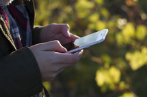 Millennial sending a text message outdoors in the fall.