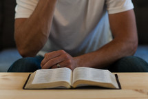 a man reading a Bible on a coffee table 