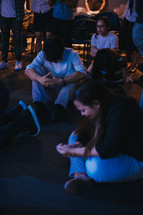 men and women sitting on the floor in prayer at a worship service 