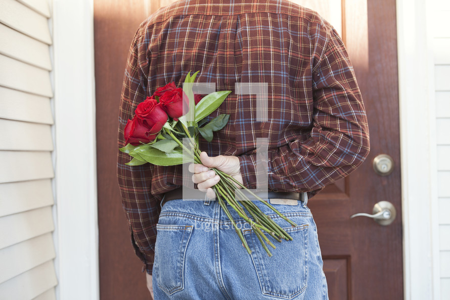 man holding roses behind his back 