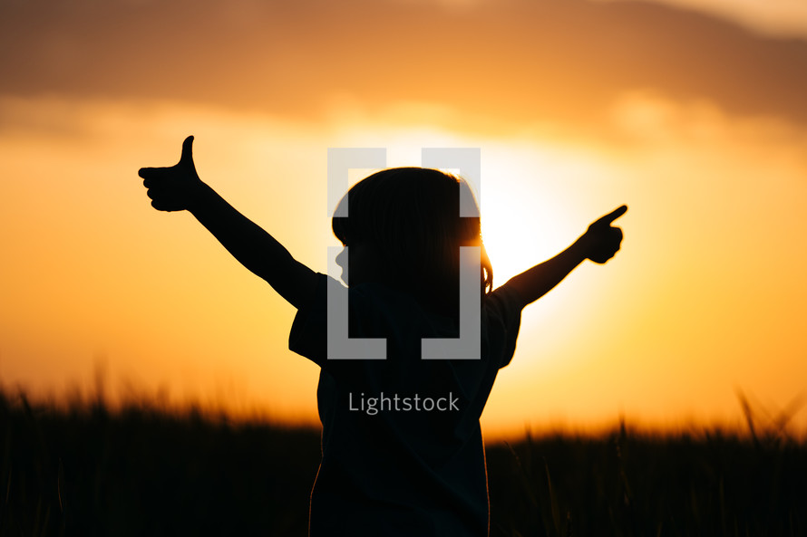 Silhouette of positive little boy with hands sign like, thumbs up gesture. Happy. High quality photo