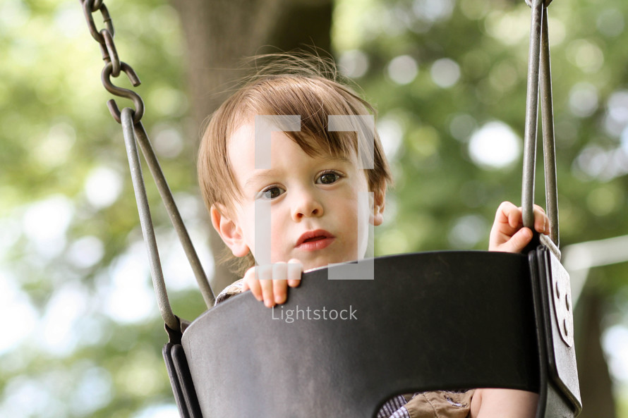 a toddler boy in a swing 