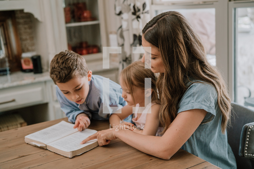 a mother reading a Bible with her children 