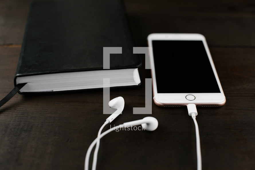 iPhone with earbuds and a Bible 