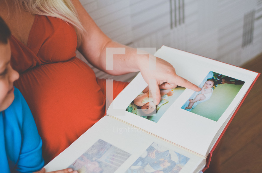 a pregnant mother looking a baby pictures of her son in a photo album