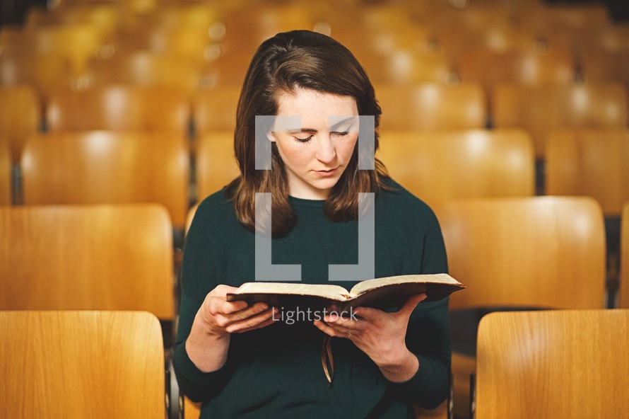 a woman reading a Bible in a church alone 