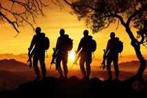 Silhouette of a group of soldiers standing on top of a mountain during sunset