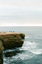 people relaxing along cliffs along a shoreline 