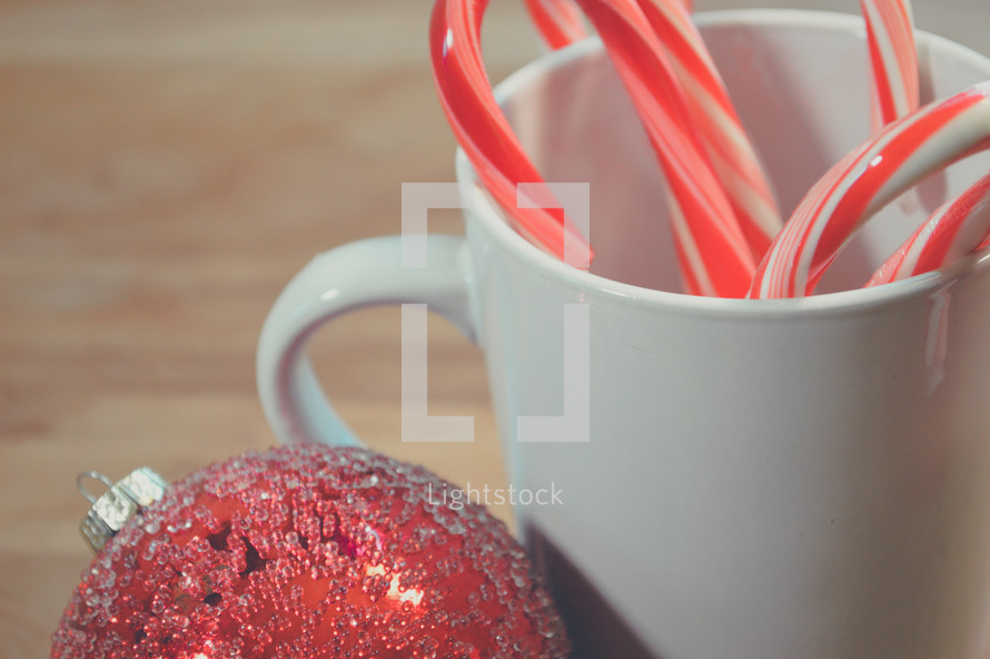 red ornament and candy canes in a mug 