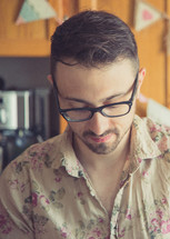 man in a floral pattern shirt standing in a kitchen 