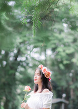 girl holding a rose with flowers in her hair 