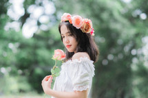 girl holding a peach rose with flowers in her hair 