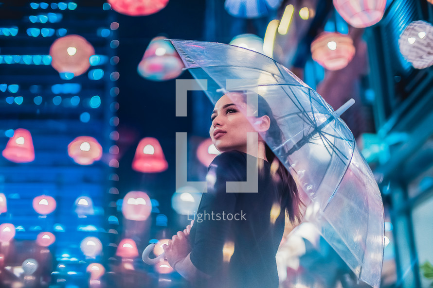 a woman carrying an umbrella at night in a city 