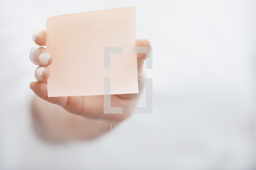 arm holding up a blank sticky note 
