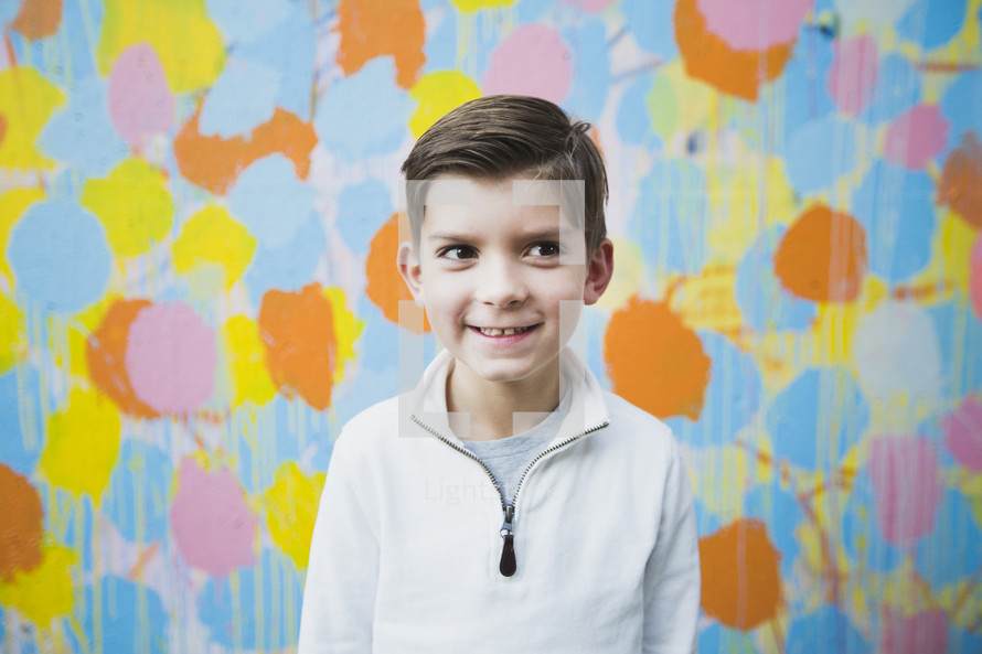 boy child standing in front of a colorful wall 