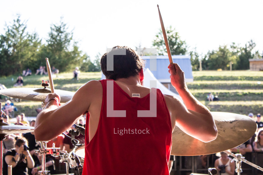a man playing drums at an outdoor festival concert 