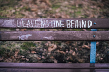 Leave no one behind written on a bench 