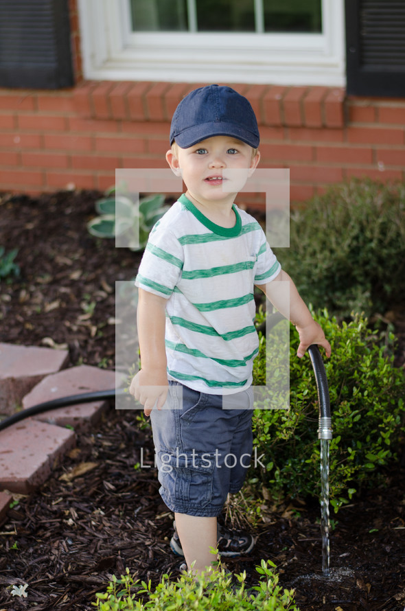 a toddler boy holding a water hose 
