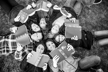 teens in a youth group lying in the grass reading Bibles