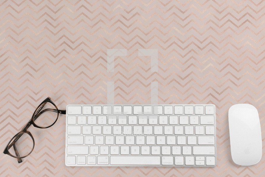 reading glasses, computer keyboard and mouse on a desk 