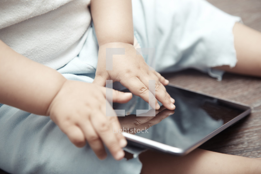 Baby with tablet computer. Close-up photo of the hands