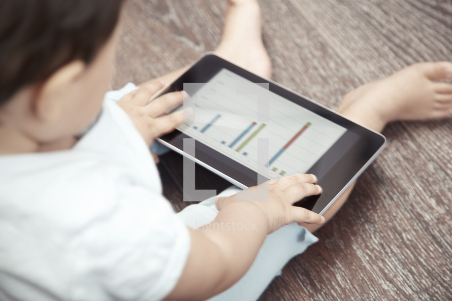 Child holding tablet computer with business chart