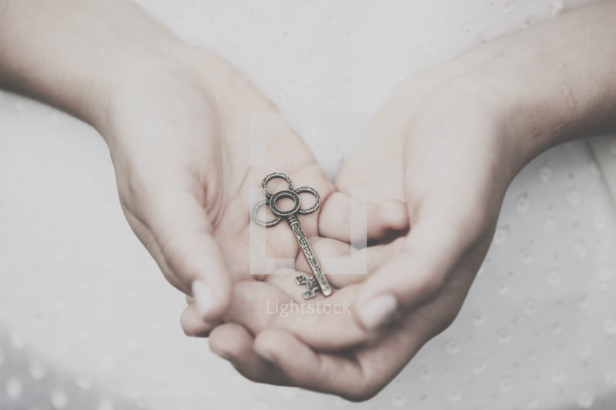 Hands holding a silver key.