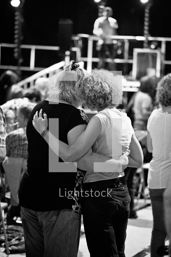 Two women praying together during a church service.