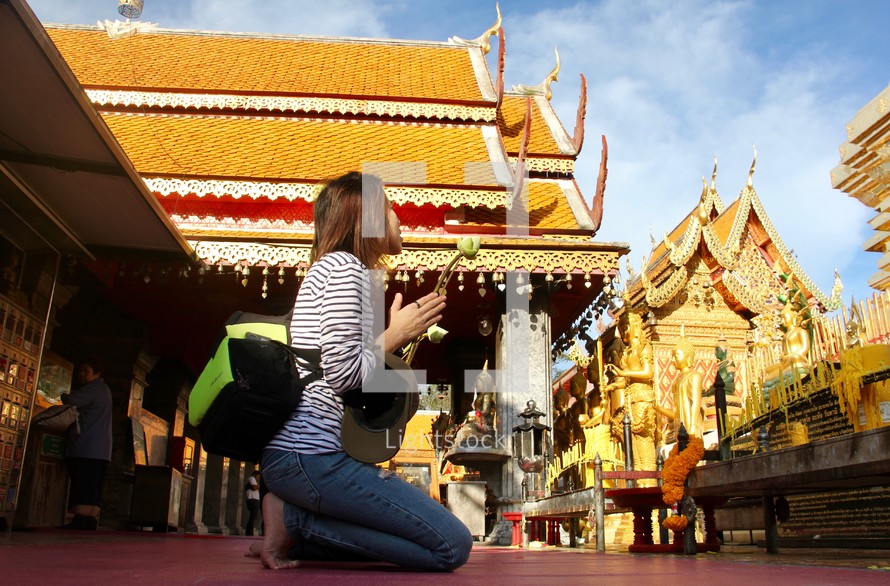 a woman kneeling down to pray in front of a shrine 