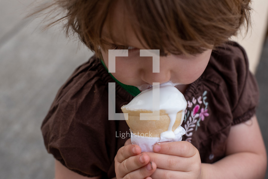 toddler girl eating an ice cream cone 