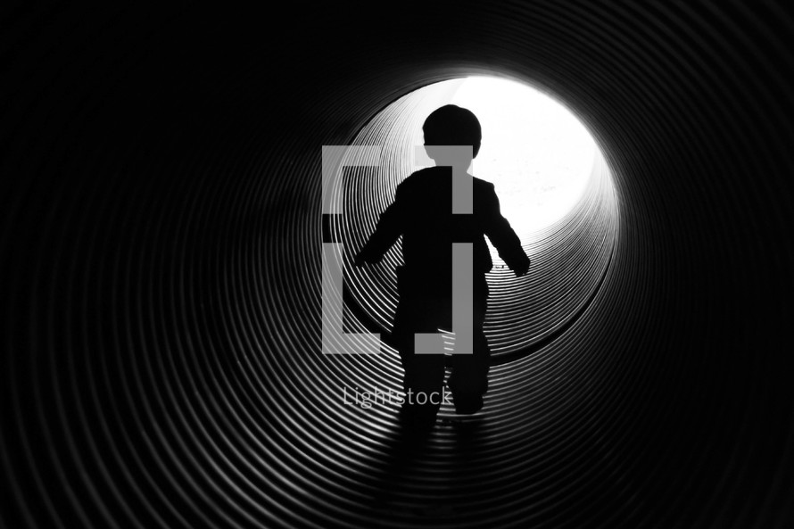 child walking through a pipe tunnel
