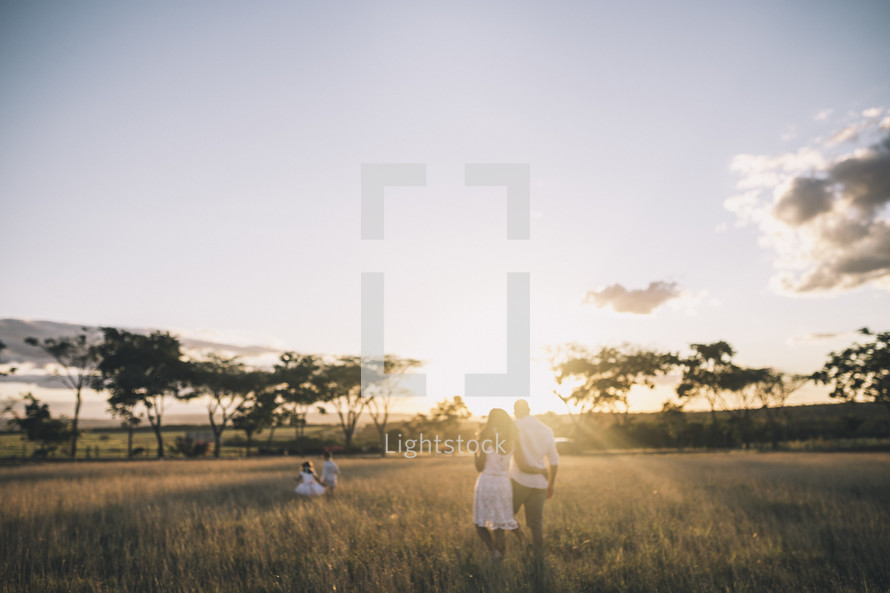 a family walking through tall grass at sunset 