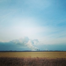 smoke from distant factories across a field