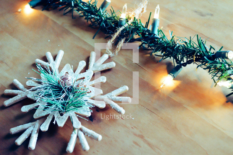 snowflake Christmas ornament and Christmas lights on wood 