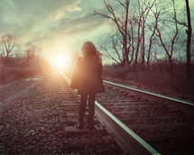 a girl walking on railroad tracks 