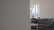 a woman sitting on a couch in front of a window reading a Bible 