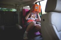 girl in a carseat eating goldfish crackers 