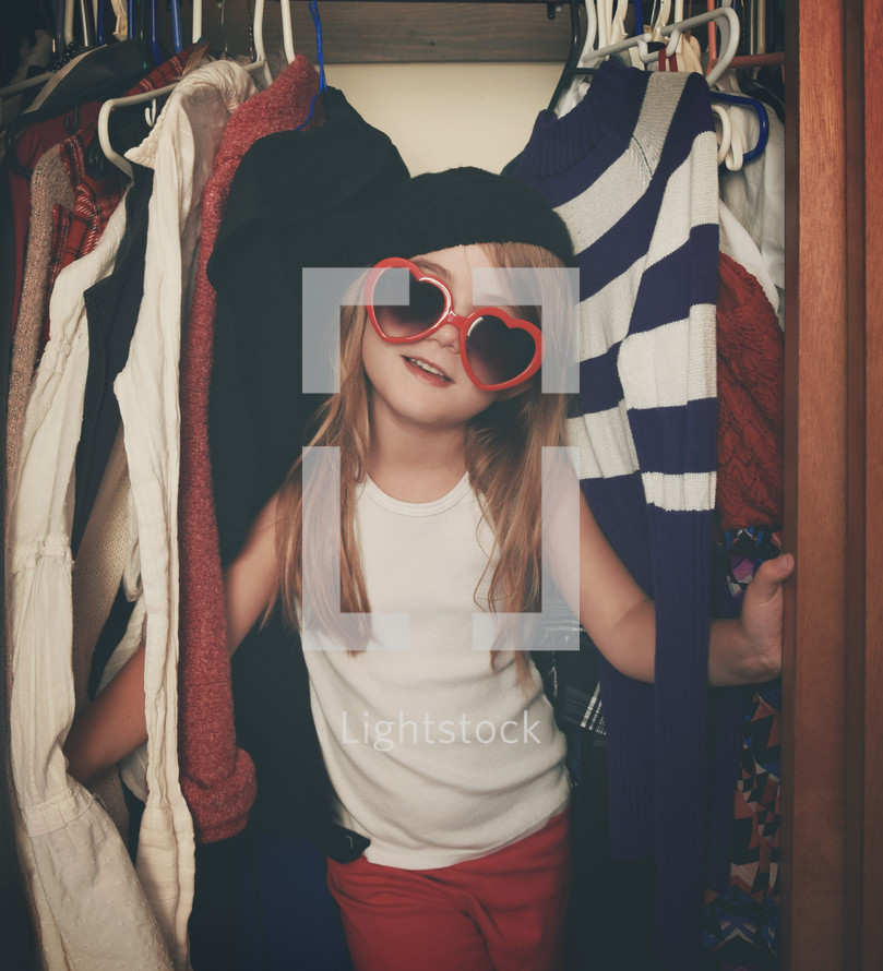 a child in a closet playing dress up 
