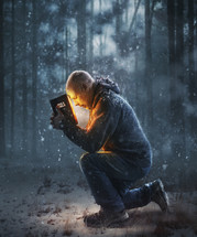 A man finds warmth from the pages of the Bible in a snowy forest.